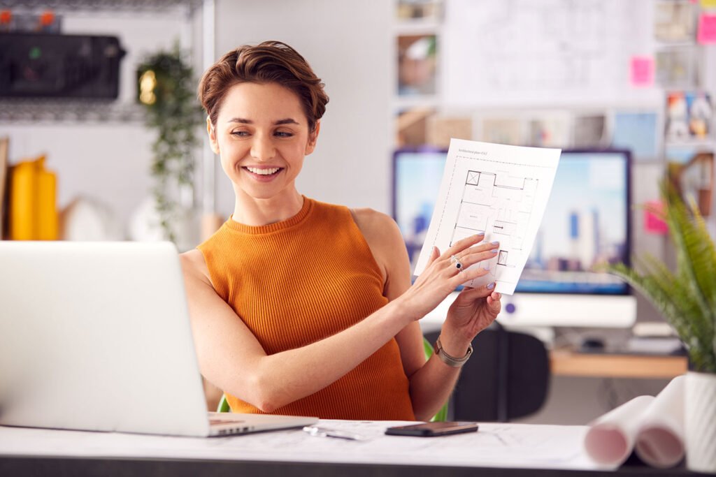 Architect working with blueprints and house model